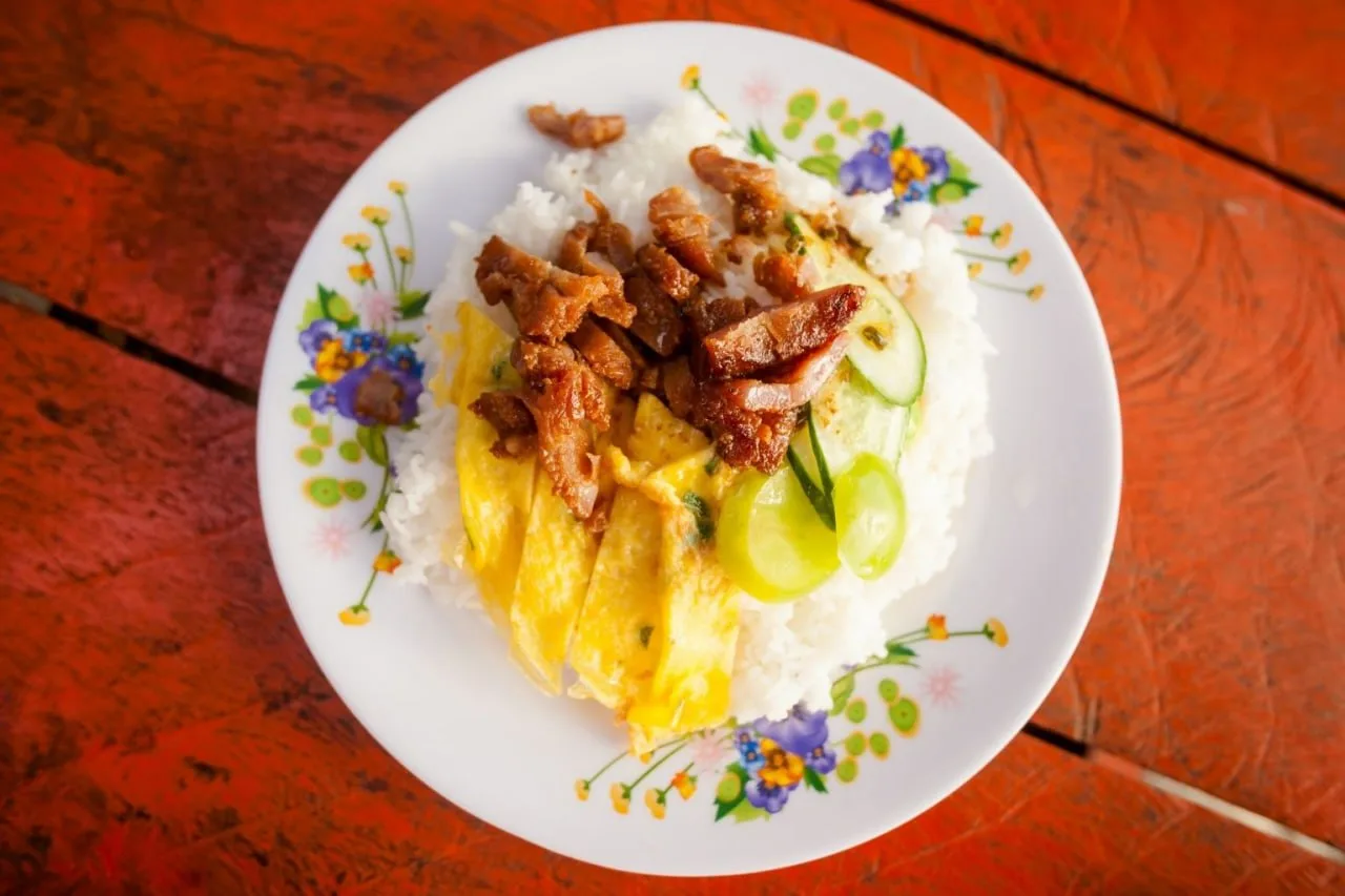 Bai sach chrouk — marinated grilled pork over rice, the classic Cambodian breakfast plate