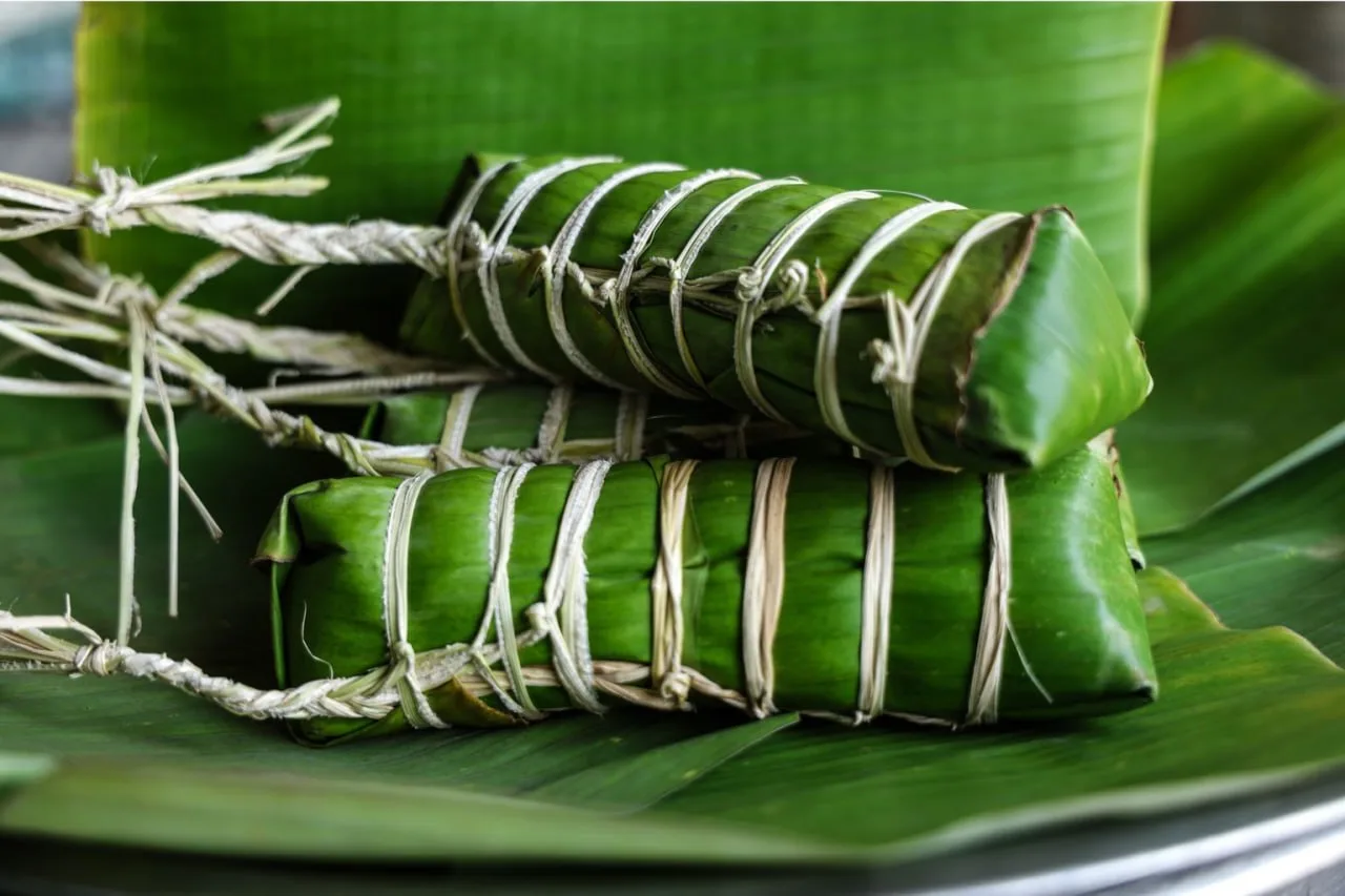 Num ansorm, sticky rice with pork and mung bean wrapped in banana leaves, made for Pchum Ben